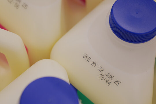 Milk containers showing expiration dates in grocery setting