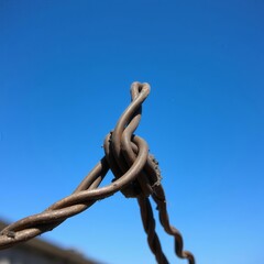 twisted iron spinning in a dynamic pattern is photographed against a background of blue sky and white clouds during the day.