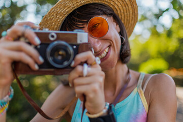 Stylish woman with a camera on the street. Portrait of a beautiful girl smiling on the street....