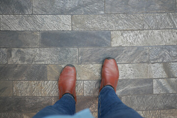 Brown leather boots on textured stone floor in urban setting