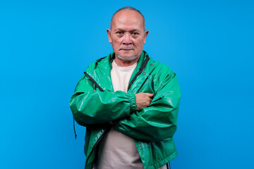 Confident Mature Asian Male With Serious Expression And Arms Crossed Over Blue Background