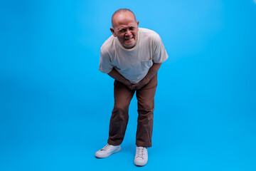 Elderly Asian Male Cover His Crotch Feeling Groin Pain Isolated On Blue Background