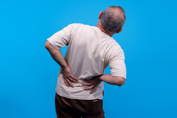 Rear View Of Senior Man Massages His Lower Back Feeling Painful Or Discomfort