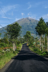 A sunny morning view of a rural road on the slopes of Mount Sumbing, Magelang, Central Java. Standing at 3,371 m, this stratovolcano is the third-highest mountain on Java, Indonesia.