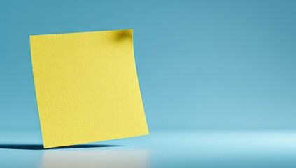 Fototapeta premium Yellow sticky note, light blue backdrop
