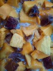 A vibrant close-up of diced mango mixed with dates, served in a creamy base. This image captures the freshness of tropical fruits, the richness of dates, and the smoothness of the creamy element.