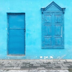 Vibrant blue wall with wooden door and window, traditional Yining, Xinjiang architecture.