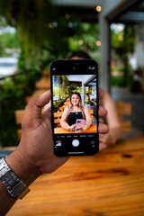 Young Woman Smiling at Outdoor Café Table with Natural Green Background