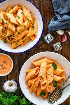 Creamy tomato and stracciatella pennone rigato noodles on wooden table