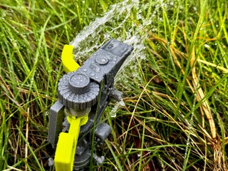 Watering the lawn with a sprinkler on a sunny day	
