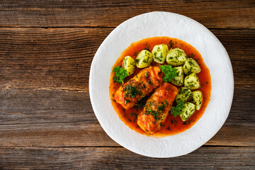 Stuffed cabbages with tomato sauce and boiled potatoes on wooden table - polish cuisine golabki