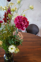 Beautiful bouquet of fresh flowers on a wooden dining table in a cozy indoor setting