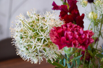 Fresh floral arrangement featuring vibrant and delicate flowers on a rustic wooden table in a cozy setting