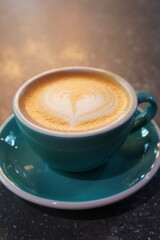 Delicious latte art in a turquoise cup observed in a cozy cafe setting during a relaxed afternoon