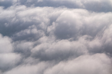 A vast sea of soft, fluffy clouds stretches endlessly below, viewed from above at high altitude, capturing the peaceful beauty and textured patterns of the sky during flight.