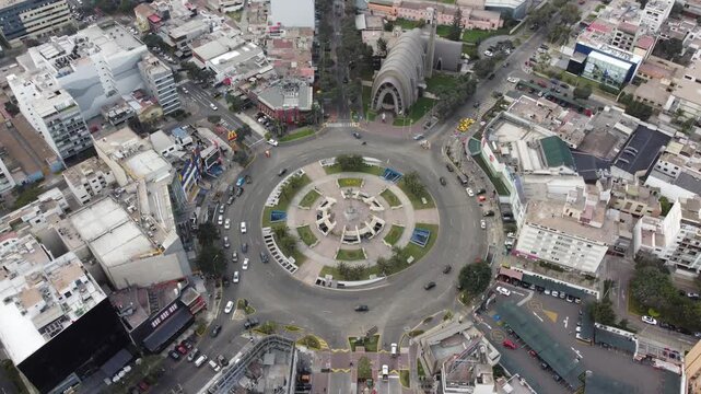 Cars driving around ovalo gutierrez roundabout in miraflores district, lima, peru, with virgen milagrosa church in background