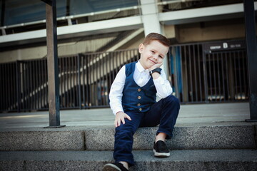 Stylish Little Boy Posing on Urban Stairs in Formal Outfit