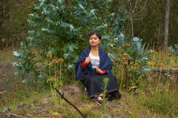 Fototapeta premium Indigenous woman wearing traditional clothes sitting in nature