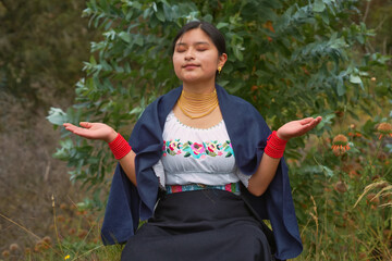 Young latin american woman meditating in nature wearing traditional andean clothing