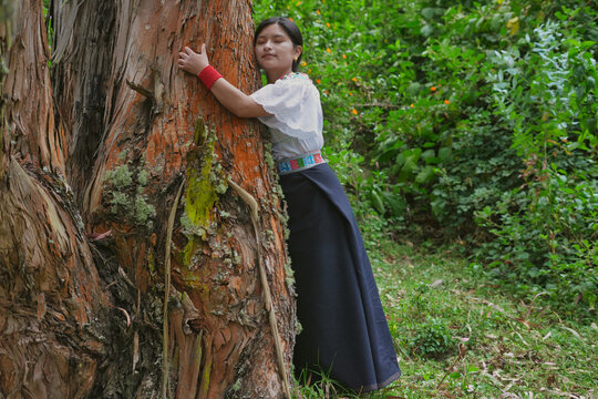 Young indigenous woman embracing a colorful tree in lush forest - Powered by Adobe