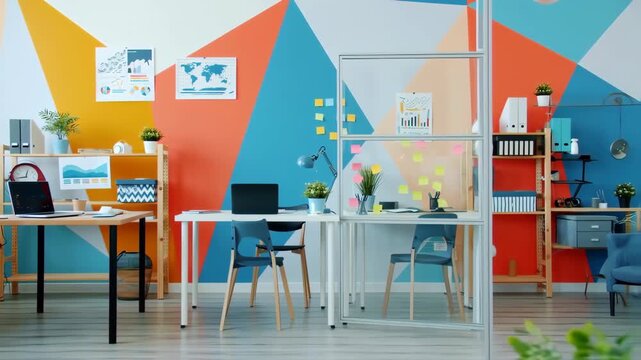 Modern colorful office workspace with desks computers and plants featuring vibrant geometric wall art