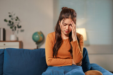 Stressed Asian woman touching her head and feeling strong headache, migraine or depression during...