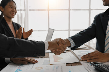 Business partners shaking hands after signing a contract during a meeting, businesswoman clapping...