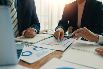 Business colleagues discussing financial charts and graphs using laptop and documents during a...