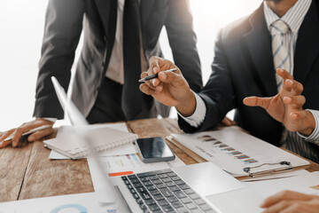Business team analyzing financial data using laptop and documents, discussing company strategy and planning future investments in a meeting