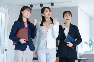 ガッツポーズをする三人のスーツを着た女性