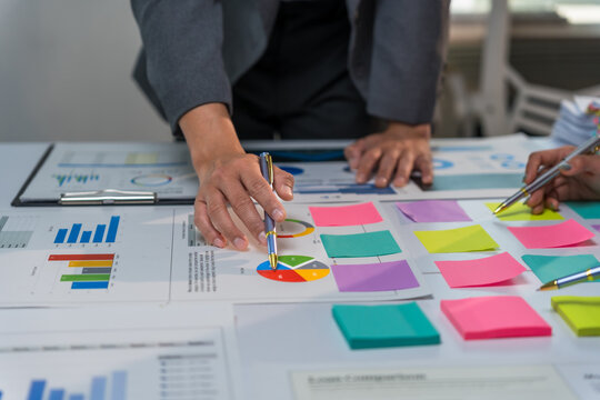 Business team analyzing financial charts and graphs using colorful sticky notes during a productive meeting, developing innovative strategies for success