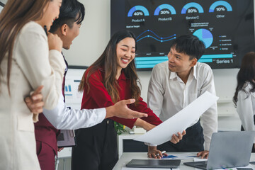 Group of young Asian businesspeople discussing financial report and corporate strategy during a...