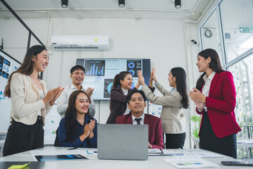 Group of young asian businesspeople celebrating success giving high five and clapping hands with...