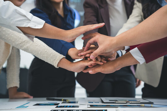 Business people joining hands together over meeting table after successful agreement showing teamwork, unity, cooperation, collaboration and support in business partnership