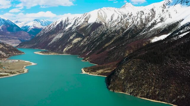Explore the breathtaking beauty of Baju Ranwu Lake surrounded by majestic mountains in a stunning aerial view