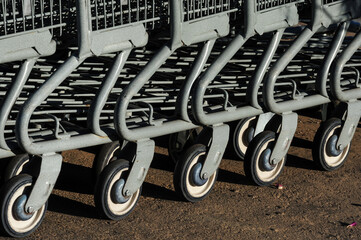 Close-up of nested shopping cart wheels aligned on pavement, suggesting preparation for customer...