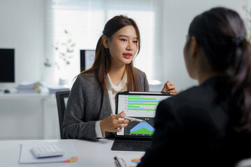 Two asian businesswomen are having a meeting in a modern office, discussing marketing strategy...
