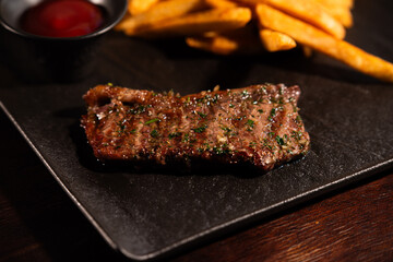 Grilled Beef Steak with French Fries and Ketchup on Black Plate