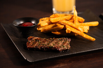 Grilled Beef Steak with French Fries and Ketchup on Black Plate