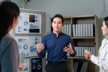 Asian businessman in blue shirt presenting company performance using charts and graphs on...