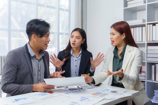 Asian businesspeople having a discussion about financial reports, they're arguing about negative results in company profits and trying to find a solution