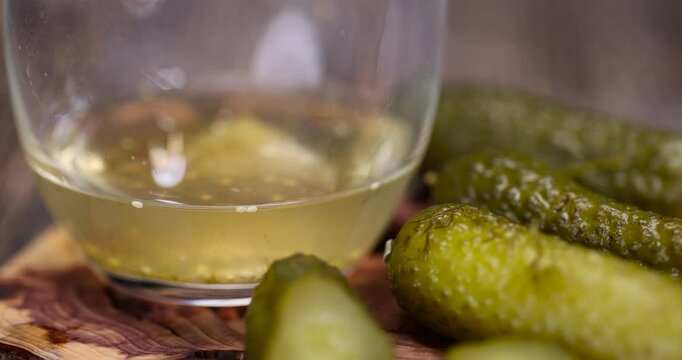 cucumbers marinade and pickled cucumbers next to a glass, poured pickle with spices and whole crispy cucumbers on a board