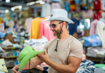 Mature man choosing hat. Male accessories store. Trendy fashion store. Handsome man trying on hat....