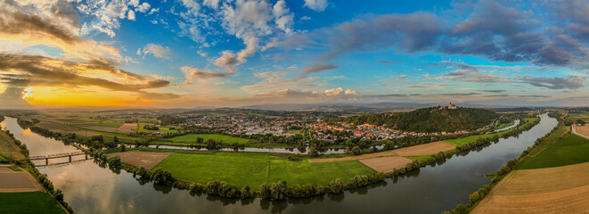 Obraz premium Schöne Landschaft mit Fluss, Sonnenuntergang und Stadt im Hintergrund