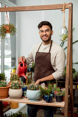 Flower shop assistant watering cactuses and looking contented