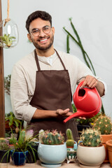 Flower shop assistant watering cactuses and looking contented