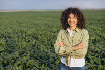 Agronomist woman smiling with crossed arms in soybean field