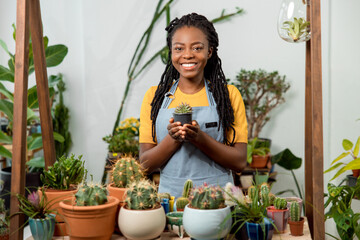 African american cute female flower shop assistant with cactuses