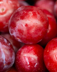 Close-up of fresh ripe red plums with natural bloom and rich texture. Ideal for food, harvest, and healthy lifestyle themes.