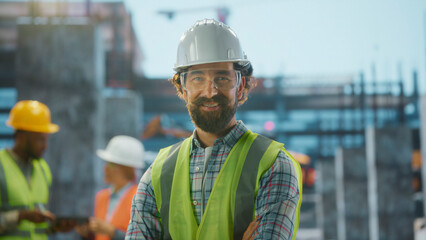 Smiling construction worker wearing hardhat and safety vest posing on construction site